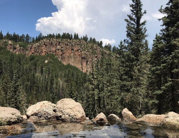 Natural hot spring pool surrounded by rocks and trees in Jemez Springs, New Mexico